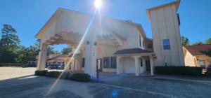 een groot wit gebouw met de zon erop bij Regency Inn & Suites By Capital O Houston IAH Airport in Humble