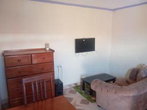 Una sala de estar con un sofá y un televisor en la pared. en Valley View, en Kiambu