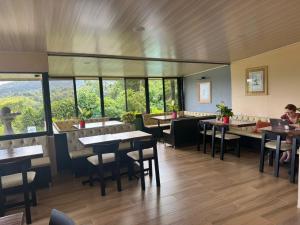 Un restaurante con mesas, sillas y ventanas. en Essence Arenal Spa & Yoga, en El Castillo de La Fortuna