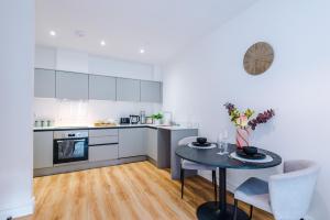 een keuken met een tafel en een kleine tafel met stoelen bij Modern Leeds Central Stay -2 min walk from station in Leeds