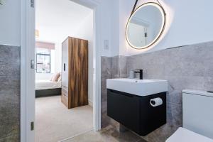 een badkamer met een wastafel en een spiegel bij Modern Leeds Central Stay -2 min walk from station in Leeds