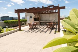 a patio with a wooden pergola and tables and chairs at Flat Beira Mar JTR Action in Maceió