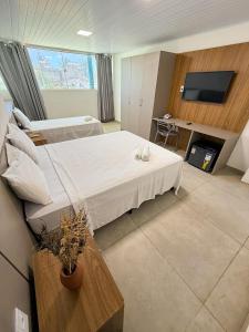 a hotel room with a bed and a tv at Amaliê Pousada in Barra de São Miguel +21 photos