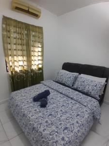 a bed with a blue comforter and a hat on it at Balqis LN Homestay in Taiping