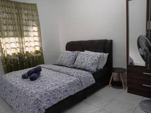 a teddy bear laying on a bed in a bedroom at Balqis LN Homestay in Taiping