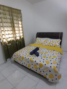 a bed with a yellow comforter with bananas on it at Balqis LN Homestay in Taiping +16 photos