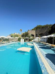 Una gran piscina con agua azul y sombrillas. en Sunlux Maison, en Isquia