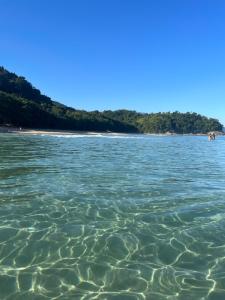 a large body of water with trees in the background at Drop House Hostel in Ubatuba