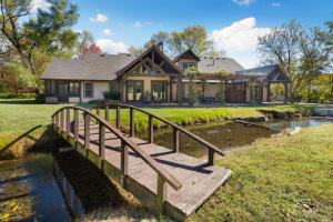 a house with a wooden bridge over a river at Whispering Brook in Springdale
