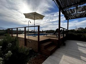 a wooden deck with an umbrella next to a pool at Small villa with pool DOXA PETRA in Sísion
