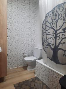 a bathroom with a toilet and a tree shower curtain at Apartamento Picos de Europa in Camaleño
