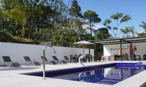 a swimming pool with chairs and an umbrella at Casa Hotel La Esperanza in Orito