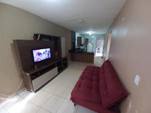 a living room with a red couch and a television at Casa Com Lazer 8 anos in Cidade Ocidental +3 photos