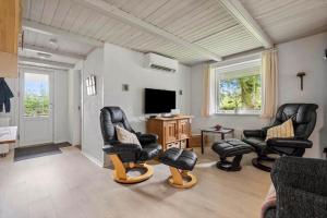sala de estar con sillas de cuero negro y TV de pantalla plana en 30073-Ulfborg-Grastensborgvej-35, en Sønder Nissum