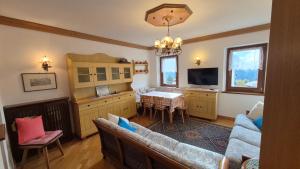 un salon avec un canapé, une table et une télévision dans l'établissement Ca' Piloni appartamento con 3 camere, à Pieve di Cadore