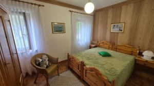 une chambre avec un lit et une chaise dedans dans l'établissement Ca' Piloni appartamento con 3 camere, à Pieve di Cadore