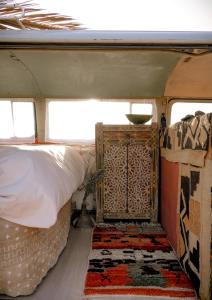 a bed and a rug in the back of a van at Amazigh van Agafay in Oumnas