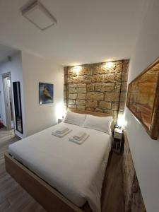 een slaapkamer met een groot wit bed en een stenen muur bij MaMa5 in Palermo