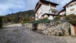 un bâtiment avec un mur de pierre à côté d'une route dans l'établissement Ca' Piloni appartamento con 3 camere, à Pieve di Cadore