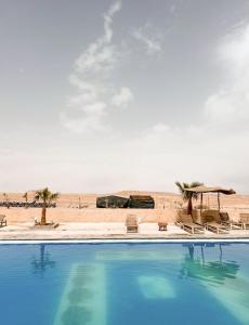 a swimming pool in front of the beach at Amazigh van Agafay in Oumnas