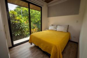 a bedroom with a yellow bed and a large window at Casa Playa Avellanas in Playa Avellana