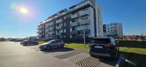 two cars parked in a parking lot in front of a building at Apartament Srebrny Quick Park Oława in Oława