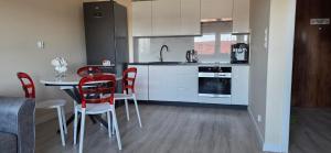 a kitchen with a table and red chairs in a room at Apartament Srebrny Quick Park Oława in Oława