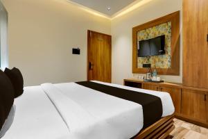 拉杰果德Hotel O The Infinity的卧室里有一张白色的床和一台平板电视