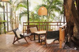 a patio with a table and chairs and palm trees at Refugio Surf Lodge in Tamarindo