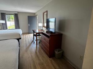 a hotel room with a bed and a desk with a television at Days Inn by Wyndham Lake City I-10 in Lake City