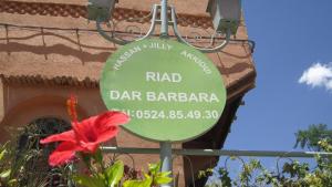 a sign in front of a building with a red flower at Riad Dar Barbara in Ouarzazate