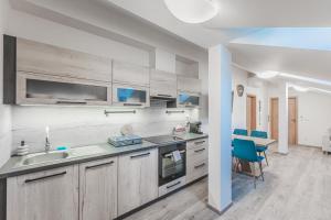 a kitchen with wooden cabinets and a blue chair at Moderní podkrovní byt 2KK u náměstí s klimatizací in Hradec Králové