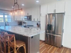 a kitchen with a stainless steel refrigerator and wooden floors at Somewhere South home in Holden Beach