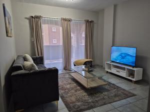 a living room with a couch and a flat screen tv at Mlangeni's Rest in Centurion +3 photos