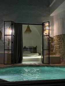 Una piscina en una habitación con la puerta abierta. en Casa Dea - bungalow Mykonos, en Hammamet Sud