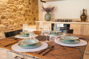 a wooden table with plates and wine glasses on it at Dimora Segreta in Pienza