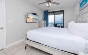 Phoenix X 1412 condo في شاطئ أورانج: غرفة نوم بها سرير ومروحة سقف