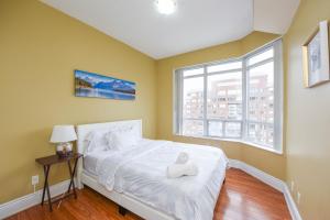 a bedroom with a white bed and a window at PlanURstay - Ideal 2BR & 2 BTH - Near SQ1 Mall in Mississauga +40 photos