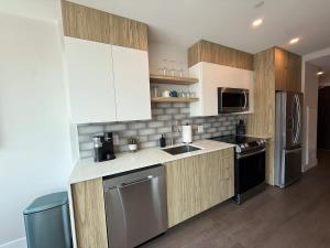 a kitchen with wooden cabinets and stainless steel appliances at Downtown Bright & Vibrant 1 BR with huge patio in Halifax