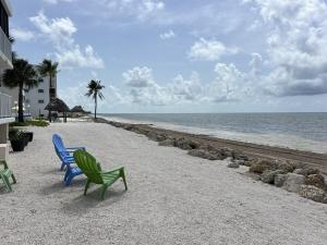 two blue and green chairs sitting on a beach at Bird of Paradise in Marathon