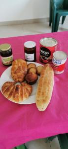 a pink table with a plate of pastries and jam at Chambre a cap skirring avec acces piscine in Cap Skirring