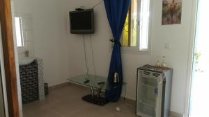 a room with a tv and a table and a window at Chambre a cap skirring avec acces piscine in Cap Skirring