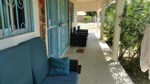 a porch with a blue couch and some plants at Chambre a cap skirring avec acces piscine in Cap Skirring