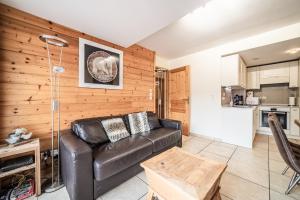 un salon avec un canapé en cuir et une cuisine dans l'établissement Le Cristal 2, aux Gets