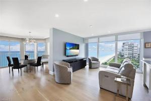 a living room with a couch and chairs and a television at Sophisticated Three-Bedroom Coastal Apartment with Fireplace in Naples +23 photos