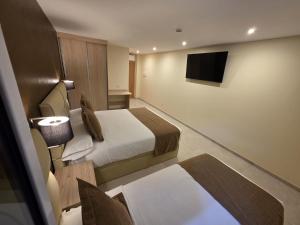 a hotel room with two beds and a television at Agora Hostal in Novelé