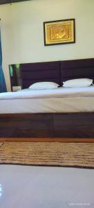 1 cama con sábanas blancas y una foto en la pared en Amri's Villa, en Mount Abu