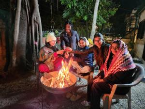 un grupo de personas sentadas alrededor de un fuego en Amri's Villa, en Mount Abu