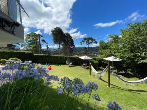 a garden with two hammocks and purple flowers at Vila de Charme Suítes in Campos do Jordão