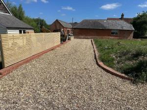 una entrada de grava con una valla y una casa en Tranquil detached barn in Sherborne St John, en Sherborne Saint John